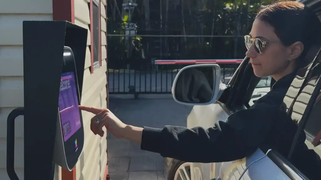 Visitor reaching from a car window to tap a vehicle gate intercom
