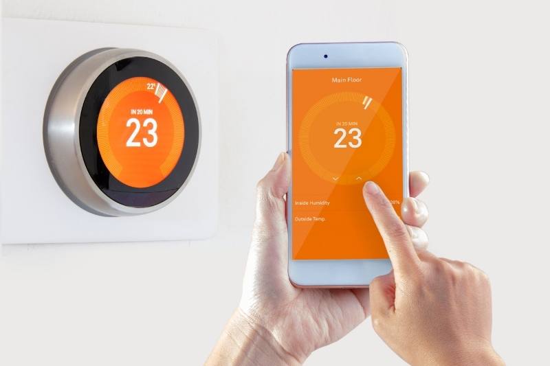 resident adjusts smart thermostat as their apartment amenity