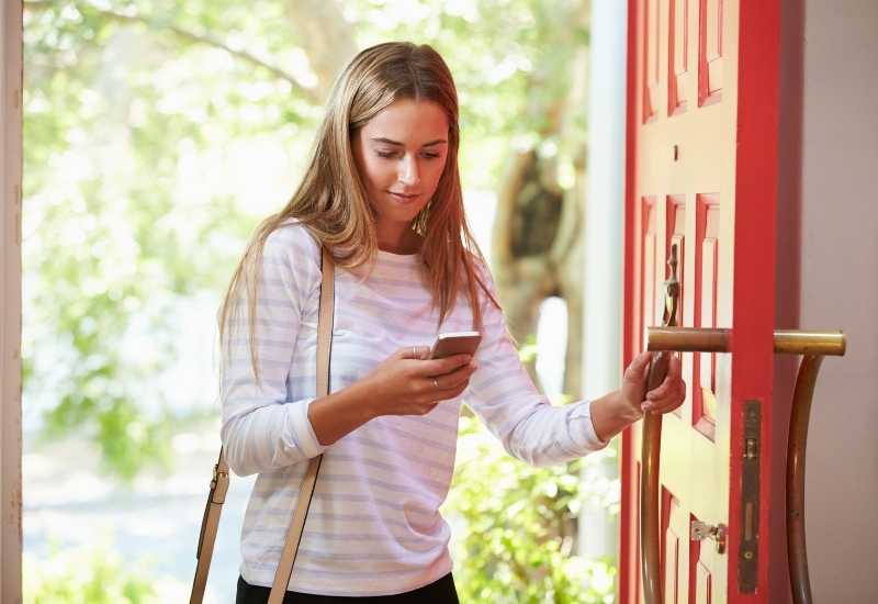 woman with smartphone opening door