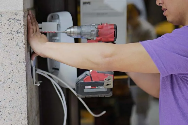 Installer uses drill to install the intercom backplate