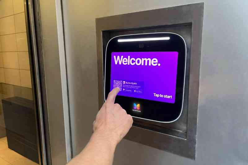 Person using a door entry intercom system to open a door.