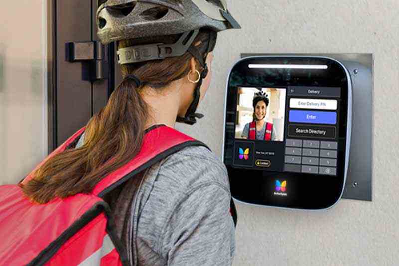 Delivery courier using a camera intercom system to enter a property.
