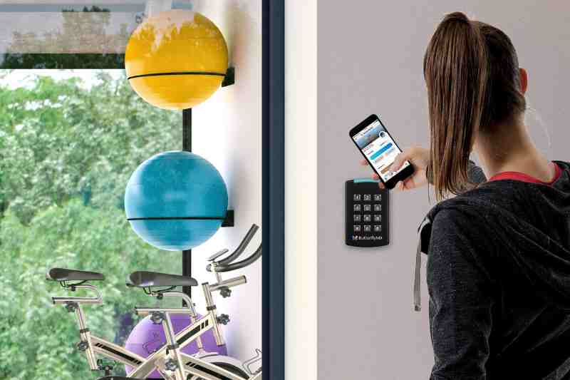 Woman using a keypad door entry system to access the gym.