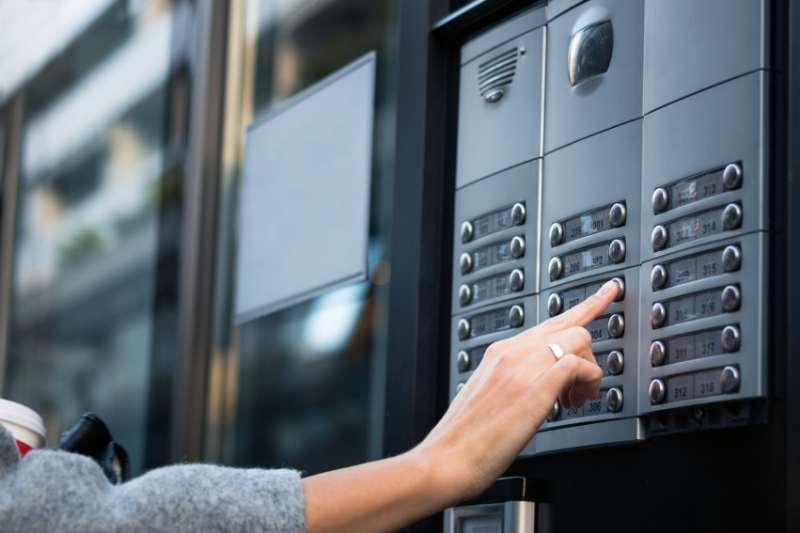 woman using a door phone intercom to request property access