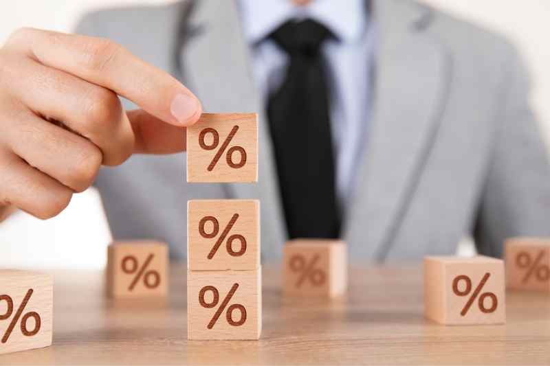 man stacking wooden blocks with percentage signs to illustrate cap rate real estate