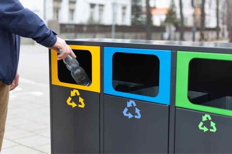 man putting bottle into yellow recycling bin for commercial waste management