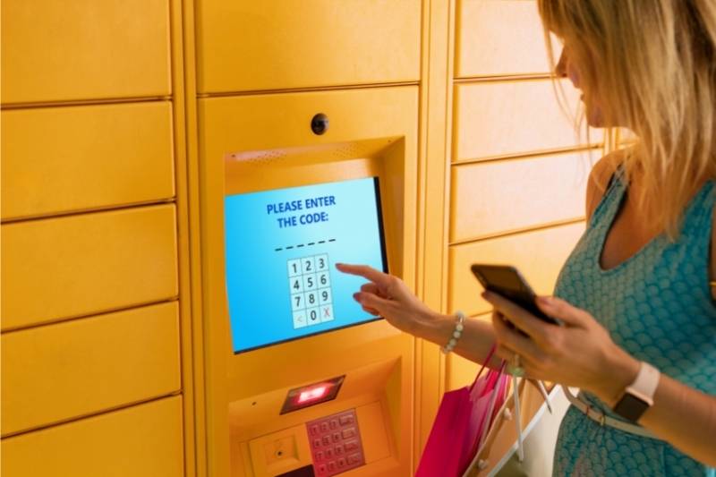 A woman retrieves her package from a smart locker terminal