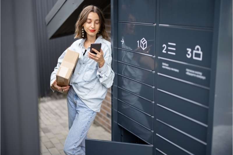 Young woman with her package beside a smart locker system