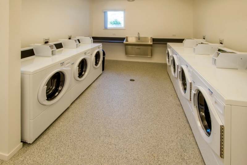 apartment laundry room with washers, dryers, and a sink