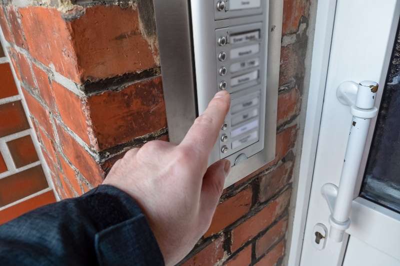 Man presses a multifamily doorbell