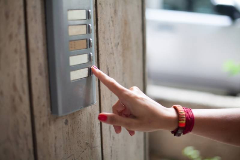 a woman rings a multi-unit doorbell