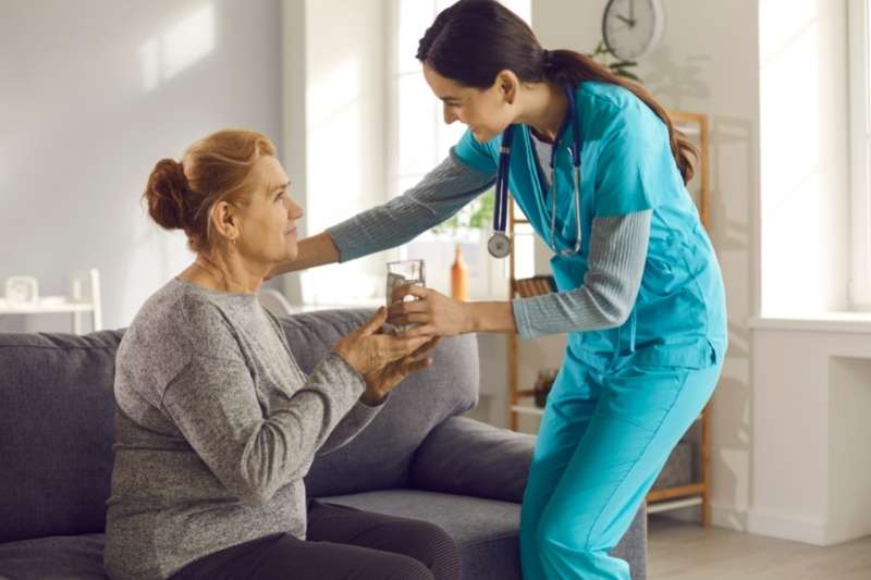 nurse hand water to elderly patient