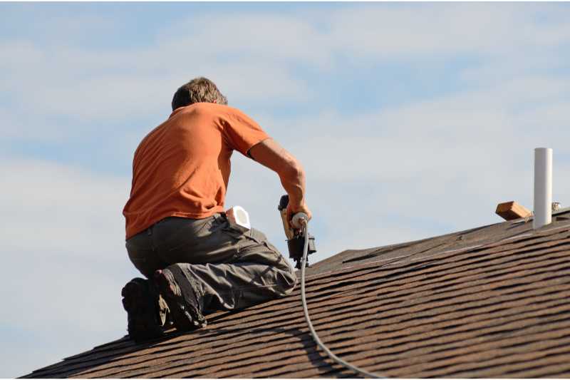 A man does roof work on a multifamily construction