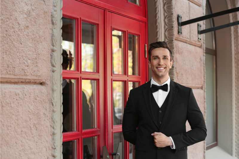 A doorman who could use doorman services technology stands outside a building