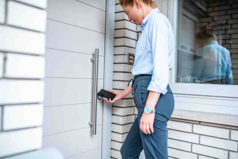 Woman opening a door using a smartphone.