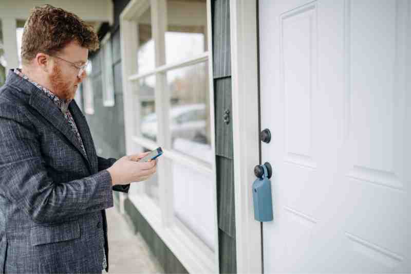 Man opening a smart key lock box for outside with his smartphone.