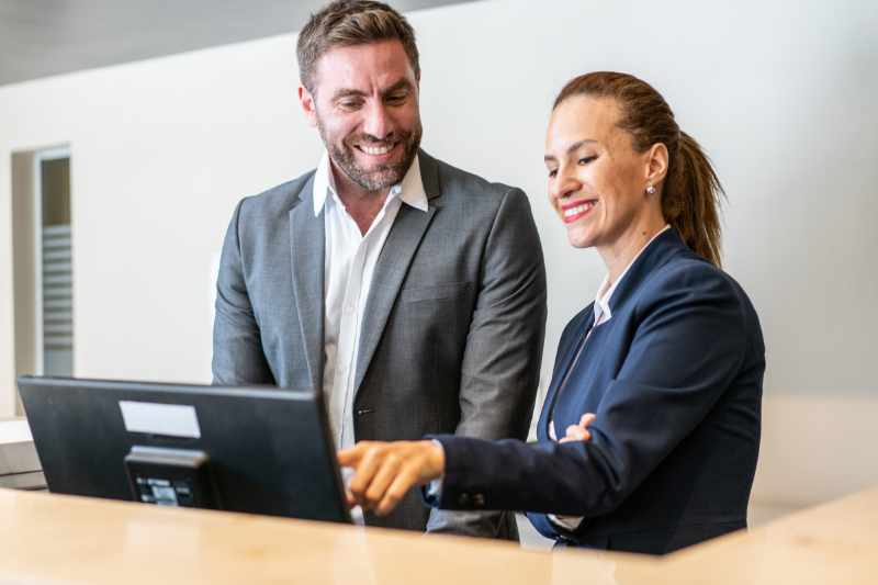 Woman showing a man how to use a front desk solution.