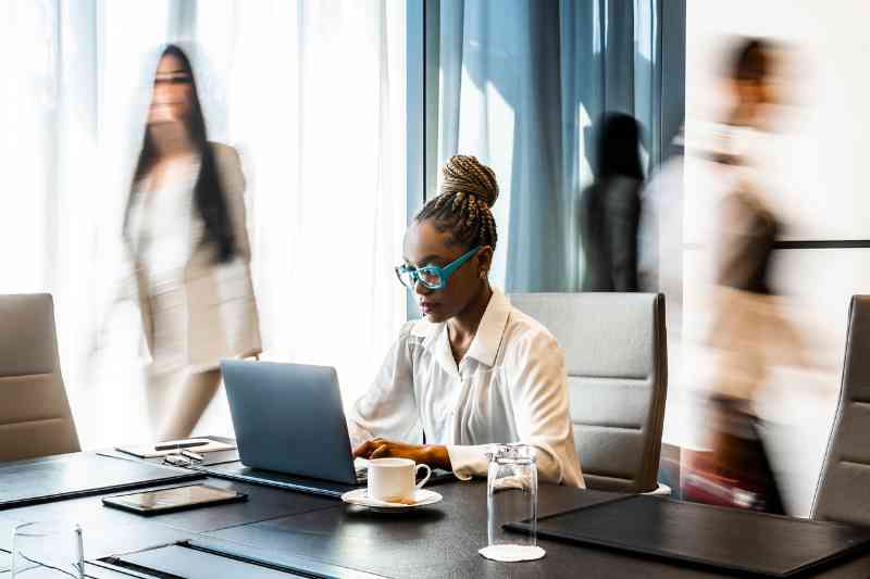 woman sitting at desk as people walk around her