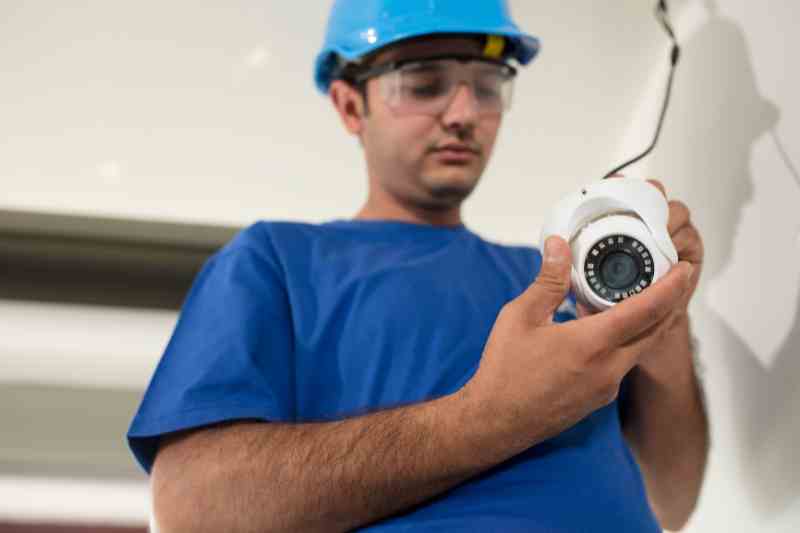 Installer inspecting commercial security cameras before installing them.