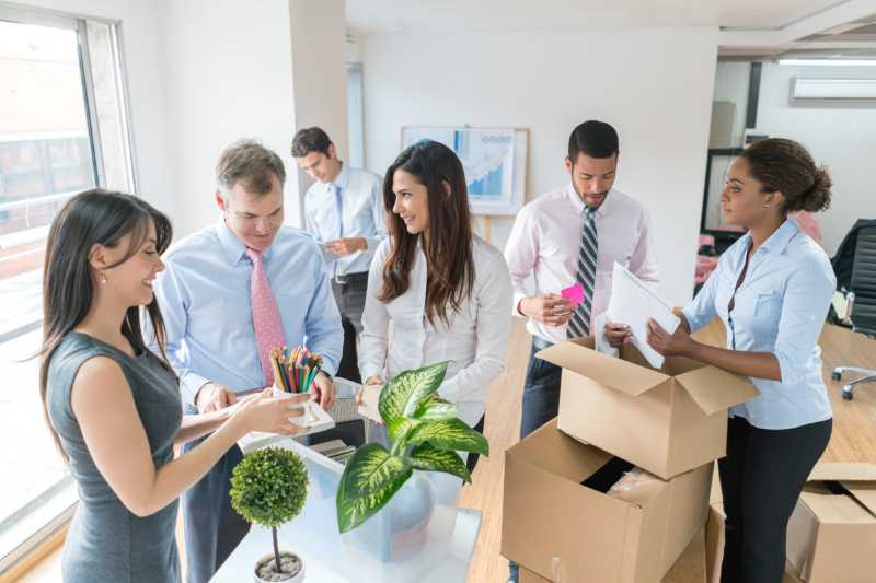 Coworkers helping each other pack for office relocation 