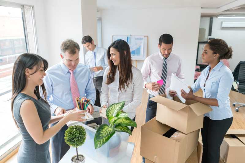 Coworkers helping each other pack for office relocation