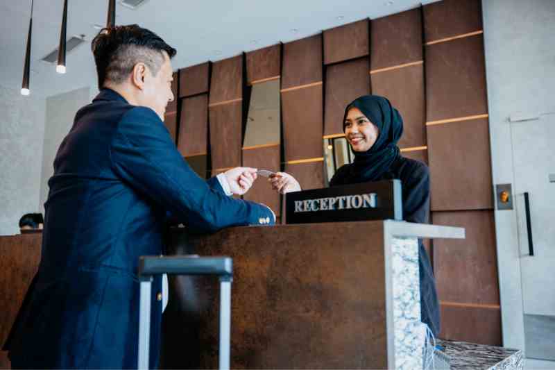 Receptionist giving a keycard to a guest to grant access with swipe card access control systems.