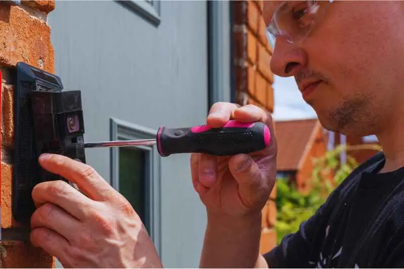 A man installs a SIP doorbell intercom system. 