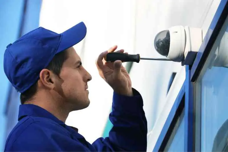 Installer placing a dome camera outside of building.