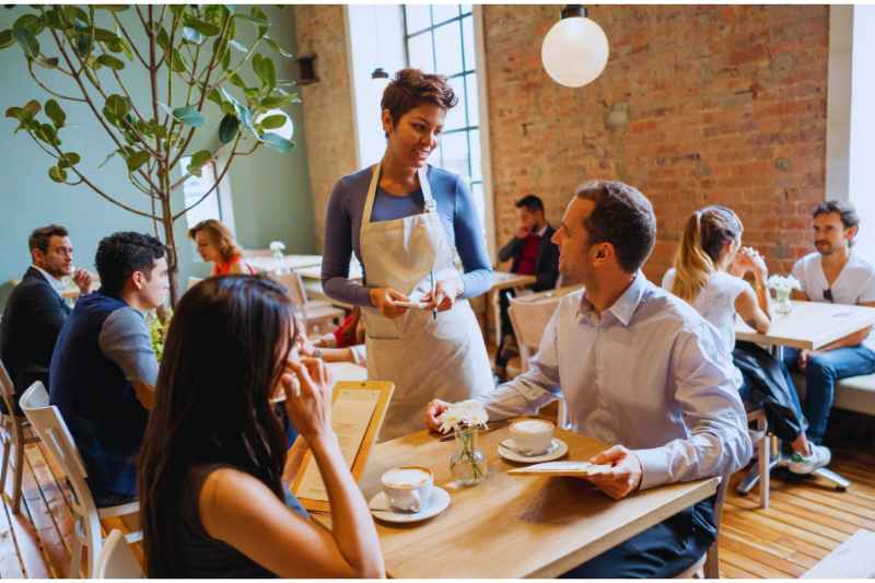 Waitstaff serve customers at a restaurant  that uses a restaurant security system. 