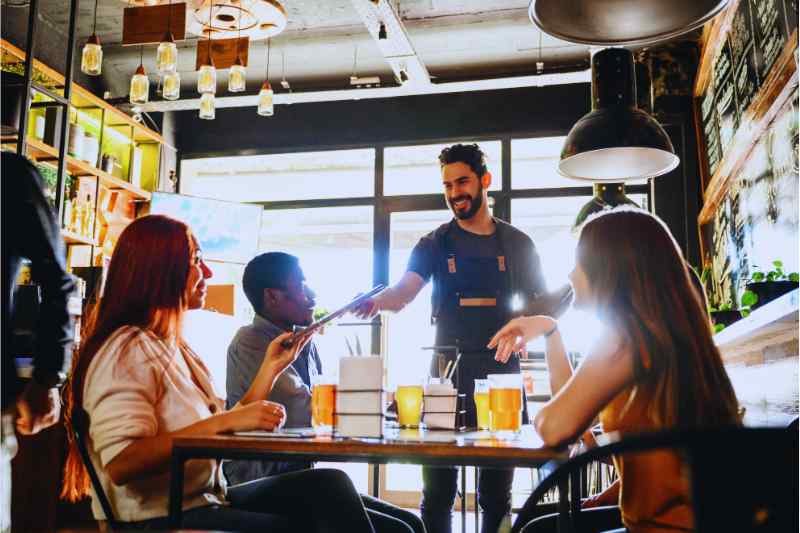 A waiter serves his table at a restaurant that uses an effective security system. 