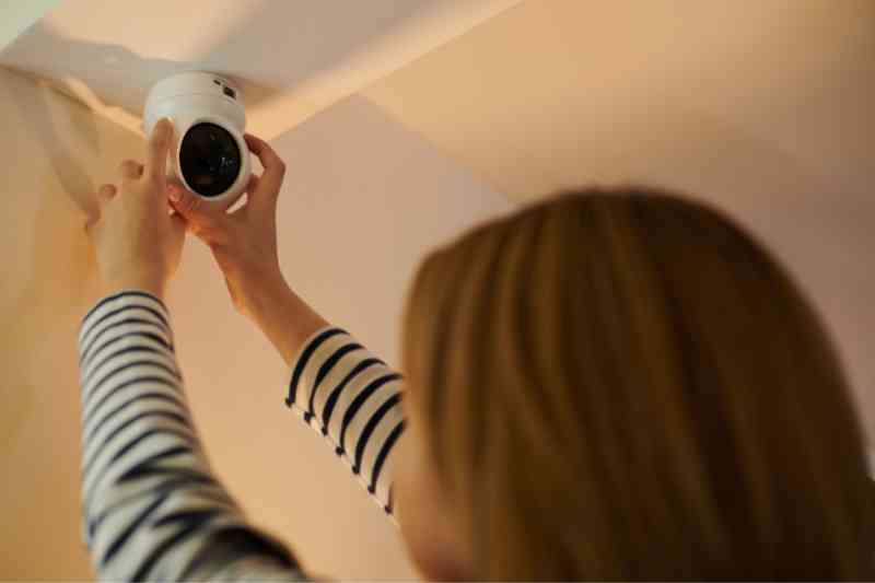 Woman placing a multifamily security camera outside of her apartment.