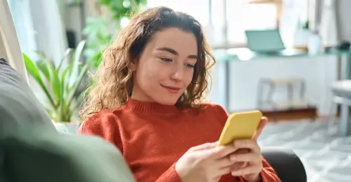 resident sitting at home on couch smiling at phone