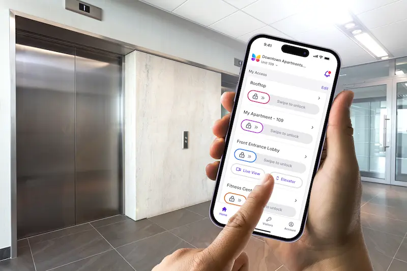 hand holding phone with butterflyMX app opened, and selecting elevatoir controls. There are building elevators in the background.