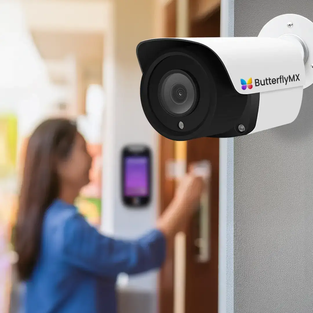 woman entering building entrance using ButterflyMX intercom, with ButterflyMX security camera above her