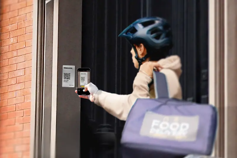 food delivery person scanning butterflymx qr code intercom with phone to gain access to building