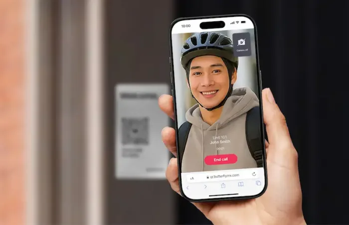hand holding phone in front of ButterflyMX QR Code Intercom, the phone screen displays a video call with the delivery person
