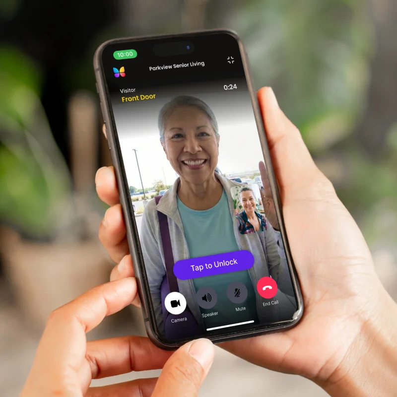 hands holding a phone that shows two students waving through a ButterflyMX intercom on a video call