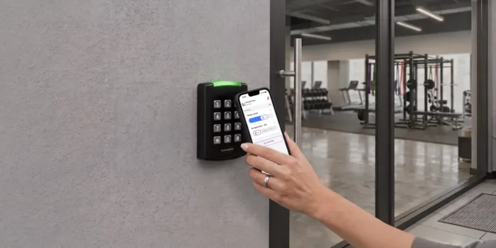 a tenant holds their ButterflyMX app up to a ButterflyMX keypad to access their building's gym