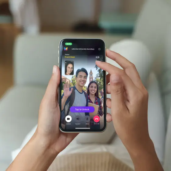student housing convenience hands holding a phone that shows two students waving through a ButterflyMX intercom on a video call